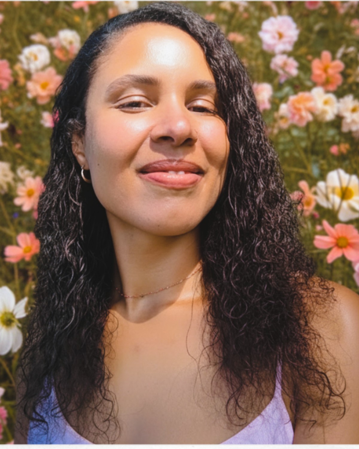 Naudia smiling, standing in a meadow of cosmos and roses